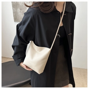 Detail of minimalist beige pebble leather crossbody bag with subtle decorative text