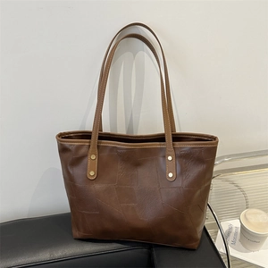 Grande borsa tote marrone retrò con trama geometrica su sedia in pelle