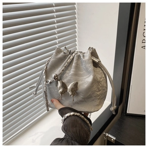 Gros plan du sac seau argenté plissé avec breloque papillon et bandoulière chaîne