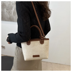 Détail du sac fourre-tout en paille tissée avec anses en cuir marron et bandoulière réglable