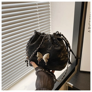 Détail d'un sac seau noir à cordon avec papillon argenté et bandoulière chaîne