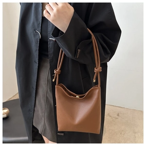 Close-up of caramel brown lychee leather phone bag with knot detail on shoulder strap
