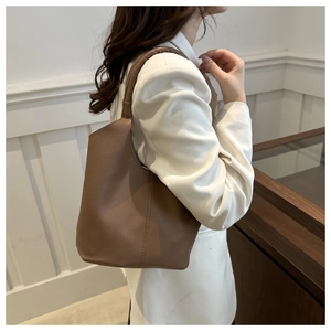 Detail view of brown lychee grain leather bucket bag showing side stitching and strap