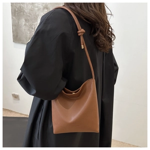 Brown litchi grain PU shoulder bag with unique knot strap and brand embossing on model