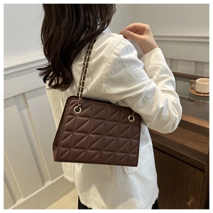 Détail d'un sac à bandoulière matelassé marron foncé avec chaîne dorée sur mannequin