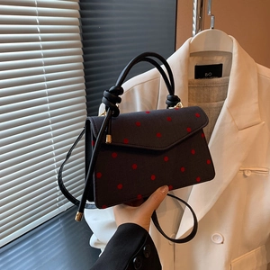 Stylish black polka dot crossbody bag with red spots and a circular top handle