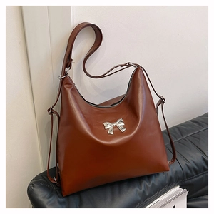 Dettaglio della borsa tote color caramello in ecopelle con fiocco d'argento e cerniera