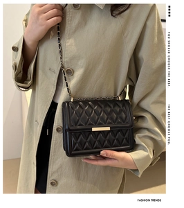 Close-up of black quilted shoulder bag with gold metal clasp and chain strap detail