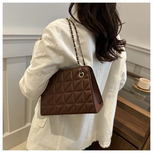 Detailed view of brown quilted chain bag worn by model showing texture and strap detail
