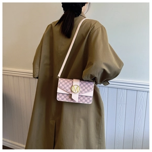 Fashionable pink monogram shoulder bag with gold M buckle worn by a model in a trench coat