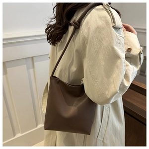 Detailed view of dark brown pebbled leather bucket bag with knotted shoulder strap