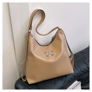 Dettaglio della borsa tote beige in pelle PU con fiocco in metallo e tracolle