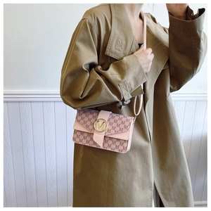 Detail view of pink M-letter monogram shoulder bag with gold logo on a trench coat