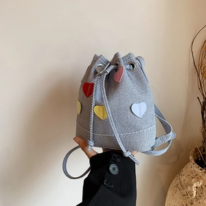 Borsa a secchiello azzurra con toppe a cuore colorate tenuta da modella in completo nero