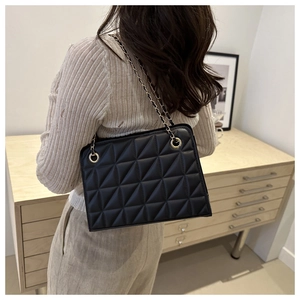 Close-up of a black quilted chain bag on a model, showing the elegant matte leather detail