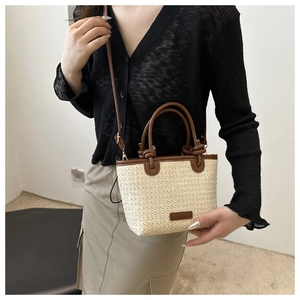 Détail d'un sac en paille tressé main avec lanières en cuir marron et design noué vintage