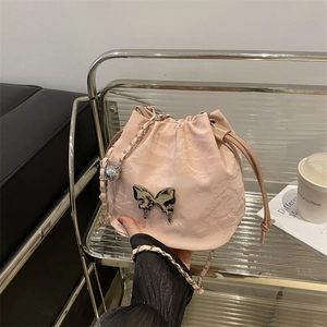 Sac seau rose à cordon avec texture plissée, papillon en métal et bandoulière chaîne