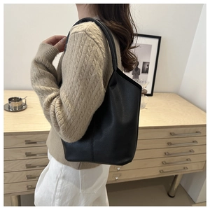 Detail of black litchi grain leather bucket bag showing soft texture on a shoulder strap