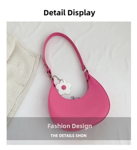 Detail of hot pink crescent underarm bag with gold logo and daisy charm accessory