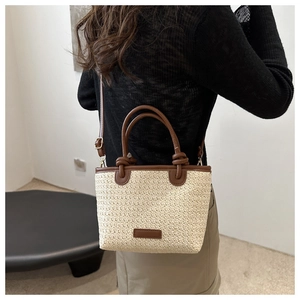 Détail de la vue arrière d'un sac bandoulière en paille tressée avec finitions en cuir brun
