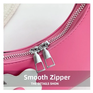 Detailed macro view of smooth dual silver metal zippers on a pink crescent handbag