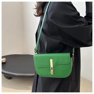 Side view of a bright green leather saddle bag with long strap and golden metal clasp