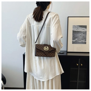 Detail of vintage brown monogram bag with a gold metal M-shaped buckle and fine strap