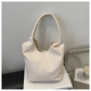 Detail of lychee textured cream bucket bag with wide strap and vertical stitching