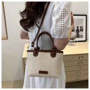 Détail du sac en paille tressée avec bordure en cuir marron et poignée nouée