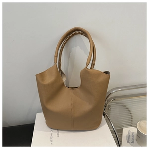 Detail of khaki litchi grain leather tote bag with round handles on a minimalist background