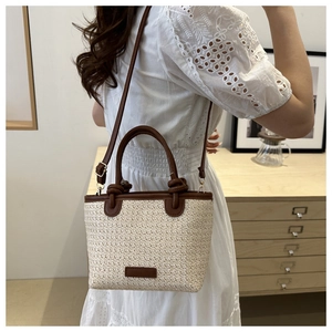 Détail du sac cabas en paille crème avec bandoulière en cuir marron sur modèle