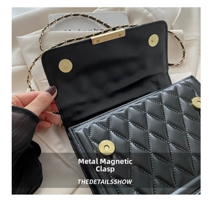 Close-up of magnetic buckle closure on a black quilted leather crossbody bag with chain