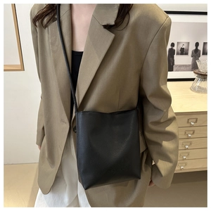 Close-up of a black pebble leather crossbody bucket bag with elegant minimalist design