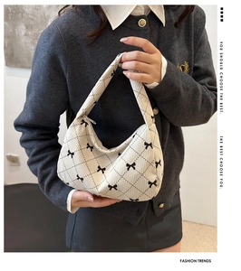 Detail of cream corduroy shoulder bag featuring black bow patterns and quilted texture