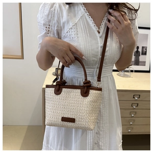 Détail du sac bandoulière en paille avec garniture en cuir porté par un modèle