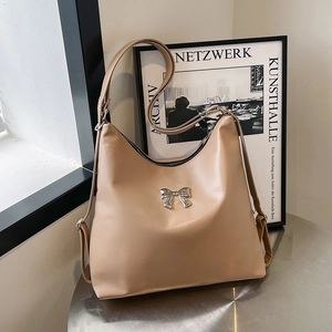 Borsa tote beige minimalista con fiocco in metallo argentato su tavolo moderno