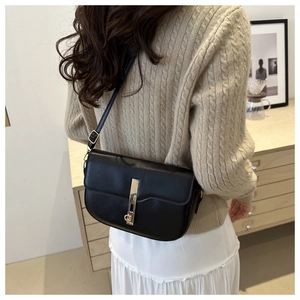 Detail of a minimalist black leather crossbody bag featuring a sleek gold metal buckle clasp