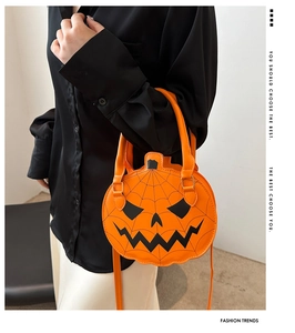 Detail of orange pumpkin bag with spider web stitching and crossbody strap on model