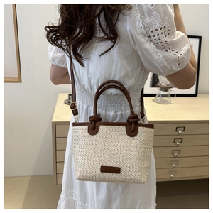 Détail d'un sac en paille crème avec poignées en cuir marron et bandoulière réglable