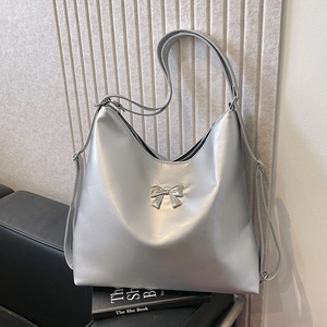 Borsa tote argento con fiocco in metallo su divano in pelle nera in stile minimalista