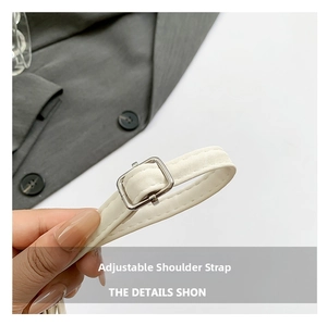 Detail view of white adjustable shoulder strap with silver buckle and fine stitching