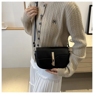 Close-up of model wearing black leather saddle bag with elegant gold metal buckle