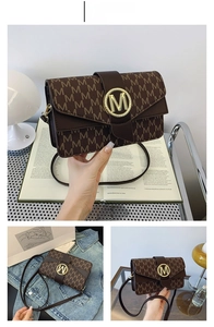 Detail of coffee-colored shoulder bag with M-letter monogram print and golden metal buckle