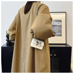 Vue arrière d'un mannequin portant un mini sac blanc avec un nœud papillon argenté