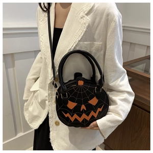 Close-up of Halloween pumpkin crossbody bag with orange jack-o'-lantern embroidery and black leather