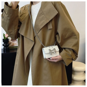 Détail du mini sac bandoulière blanc avec nœud argenté et fine bandoulière en chaîne