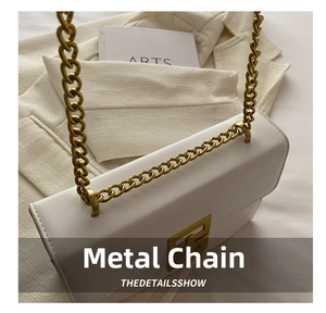 Close-up of white matte shoulder bag with chunky gold chain strap and metal clasp detail