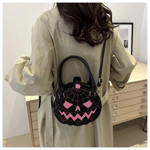 Close-up of black pumpkin handbag with pink spider web embroidery and cute face detail