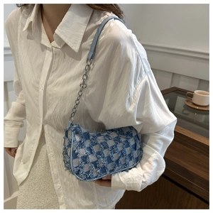 Detail of denim blue and white plaid crossbody bag with trendy fringe edges and metal chain