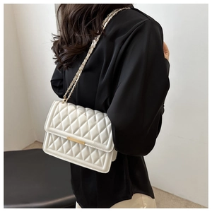 Detailed back view of a white quilted crossbody bag with a gold chain strap on a model